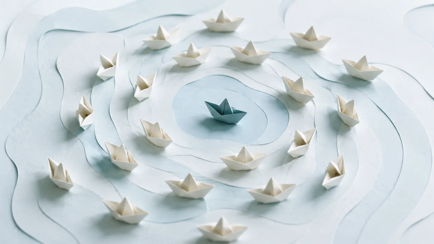 Calm illustration of paper boats coordinating around a differently colored central boat
